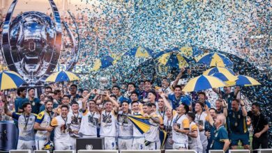 El plantel de Rosario Central celebra en el podio de campeón de la Supercopa Internacional con papelitos y paraguas azul y amarillo
