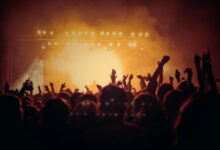 Público con las manos en alto frente al escenario en un recital