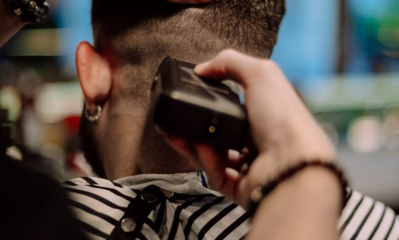 Barbero haciendo un corte degradado con máquina a un hombre