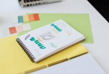 Cuaderno con bocetos de diseño de logo y muestras de color sobre un escritorio