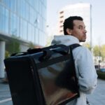 Repartidor con mochila térmica de delivery caminando por una calle de la ciudad