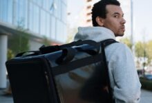 Repartidor con mochila térmica de delivery caminando por una calle de la ciudad