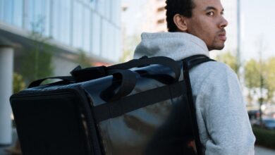 Repartidor con mochila térmica de delivery caminando por una calle de la ciudad