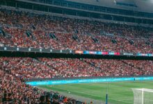 Estadio de fútbol iluminado de noche con las tribunas llenas