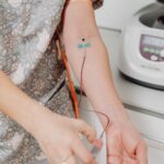 Profesional de la salud con guantes durante una extracción de sangre en el brazo de un paciente