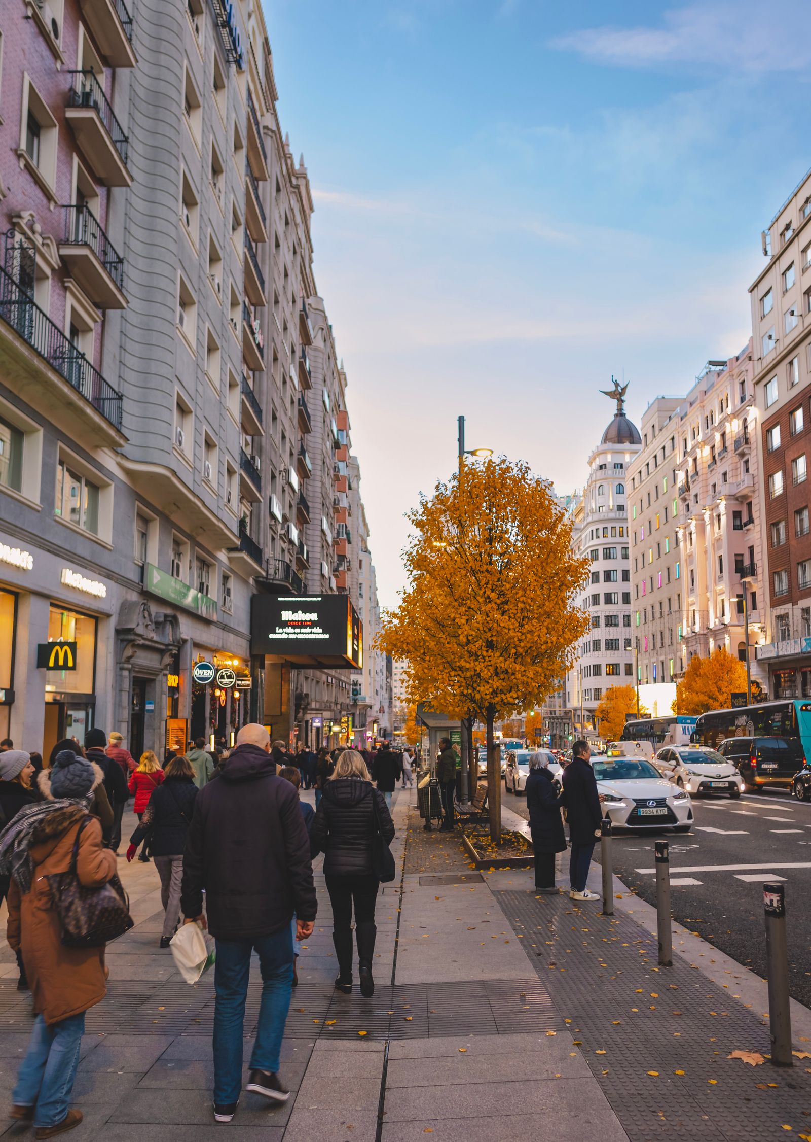 Gran Vía de Madrid con peatones y árboles otoñales