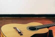 Guitarra acústica de madera apoyada en el piso