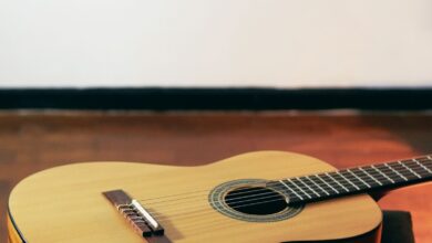 Guitarra acústica de madera apoyada en el piso