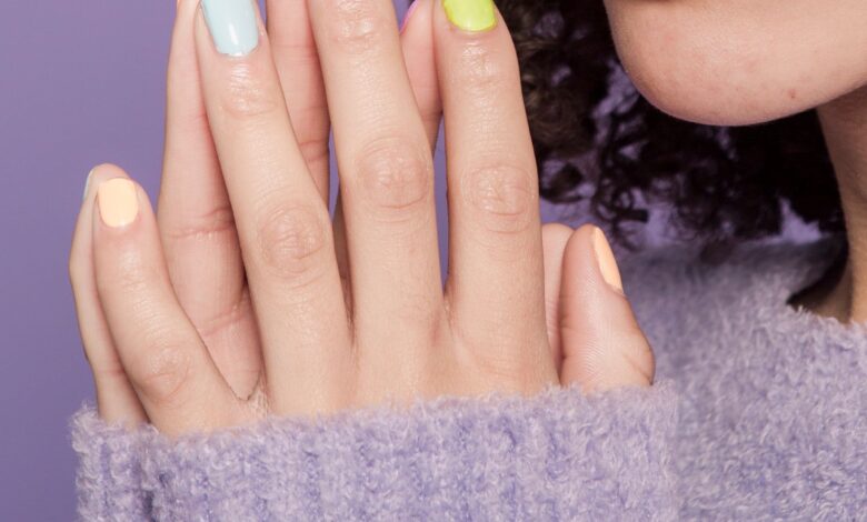 Manos de mujer con uñas pintadas en tonos pastel
