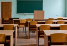 Aula vacía con pupitres de madera y pizarrón verde
