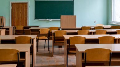 Aula vacía con pupitres de madera y pizarrón verde