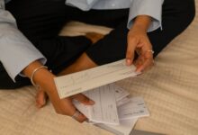 Persona revisando papeles y boletas junto a una computadora portátil