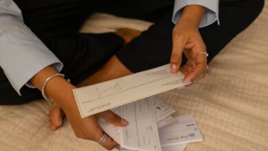 Persona revisando papeles y boletas junto a una computadora portátil