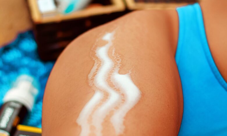 Mujer con protector solar recién aplicado en el brazo en la playa