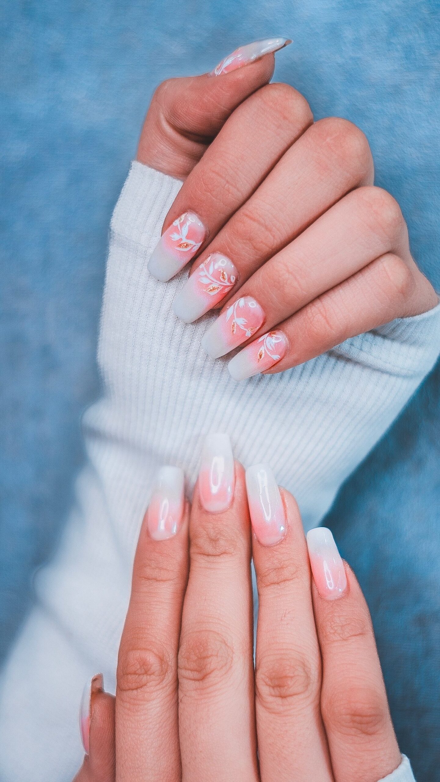 Manos con uñas largas en degradé rosa y blanco, estilo aura