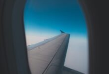 Vista del ala de un avión desde la ventanilla, sobre el cielo