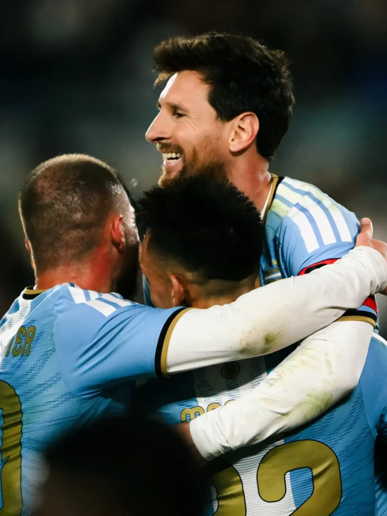 Messi sonriendo en un abrazo grupal con compañeros de la Selección después del gol.