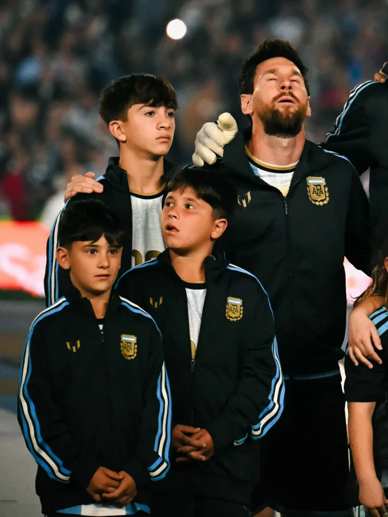 Messi con la mirada al cielo durante el himno, rodeado de sus tres hijos con camperas de la Selección.