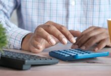 Persona usando una calculadora en el escritorio