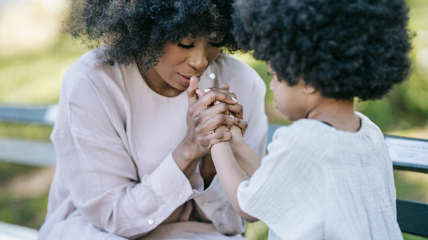 Una mujer y una nena de la mano, juntas al aire libre
