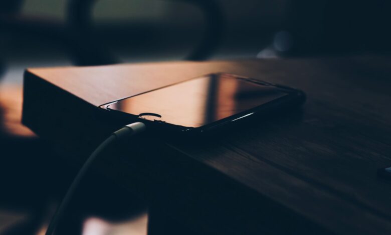 Celular conectado al cargador sobre una mesa de madera