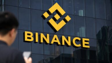 Fachada de un edificio con el logo de Binance y una persona mirando el celular