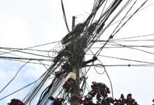 Poste con una maraña de cables aéreos en una calle de Rosario