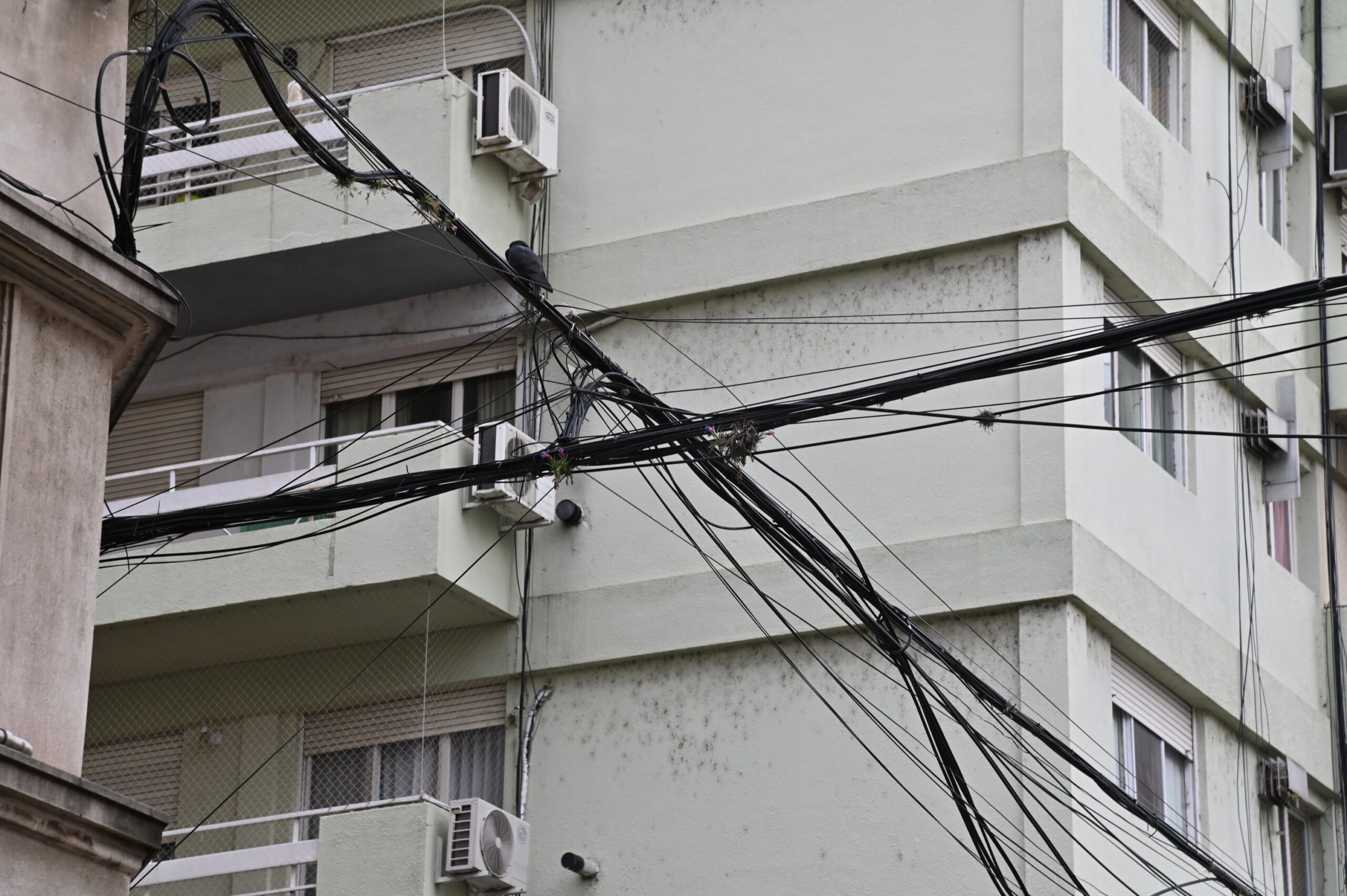 Cables aéreos cruzando la fachada de un edificio en el centro de Rosario