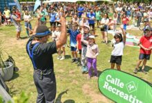 Chicos y familias hacen actividad física junto a un cartel de Calle Recreativa en un parque de Rosario