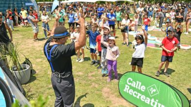 Chicos y familias hacen actividad física junto a un cartel de Calle Recreativa en un parque de Rosario