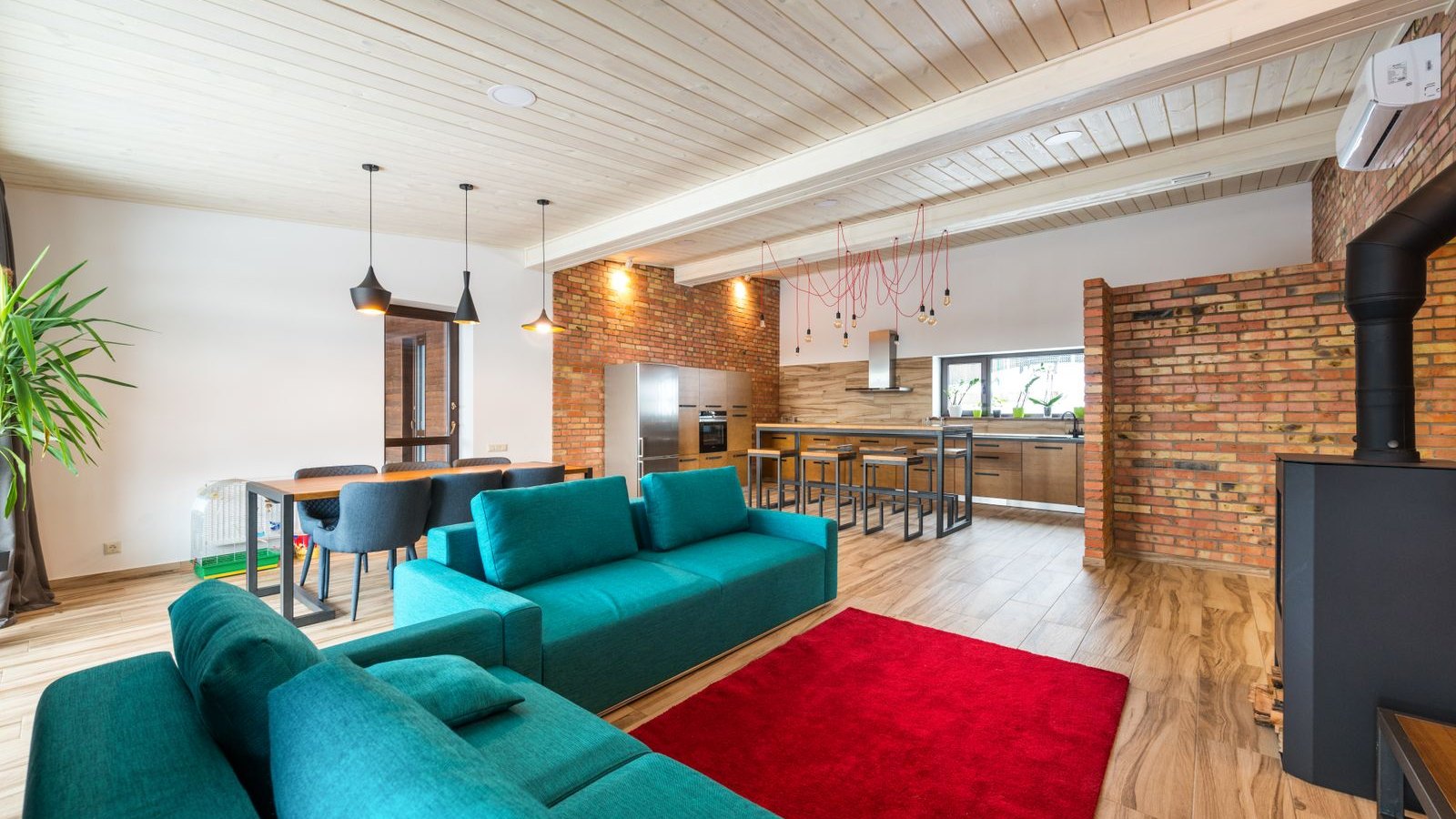 Living moderno con paredes de ladrillo, sillón verde y alfombra roja