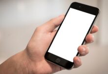 Mano sosteniendo un teléfono celular con la pantalla en blanco