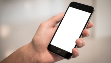 Mano sosteniendo un teléfono celular con la pantalla en blanco