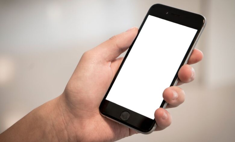 Mano sosteniendo un teléfono celular con la pantalla en blanco