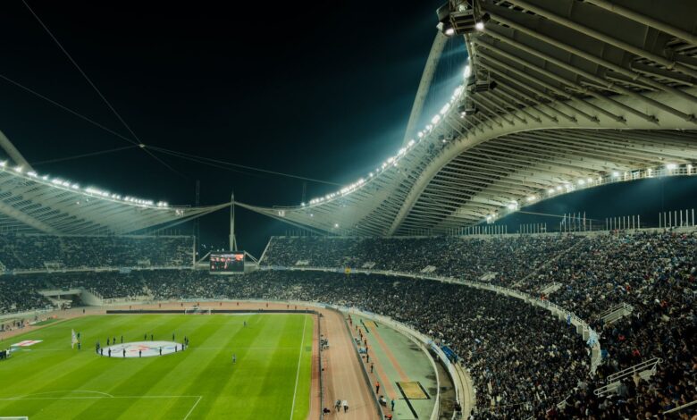 Estadio de fútbol iluminado de noche con la tribuna llena