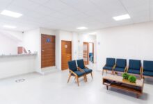 Sala de espera luminosa de un centro de salud con sillas azules y mostrador de admisión