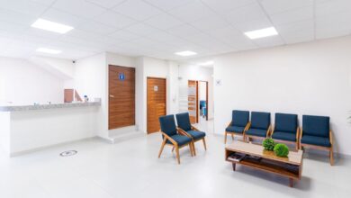 Sala de espera luminosa de un centro de salud con sillas azules y mostrador de admisión