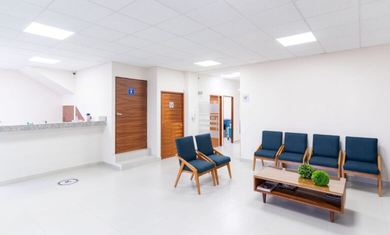 Sala de espera luminosa de un centro de salud con sillas azules y mostrador de admisión