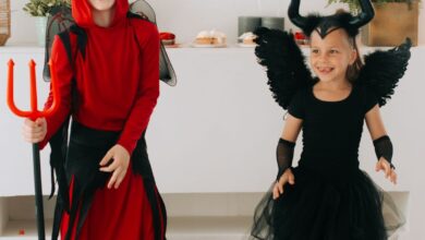 Dos chicos disfrazados de diablo y ángel oscuro riendo en una fiesta de Halloween