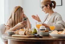 Madre y adolescente conversando en la mesa con un celular en la mano