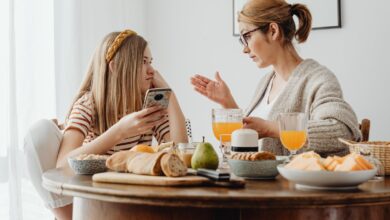 Madre y adolescente conversando en la mesa con un celular en la mano