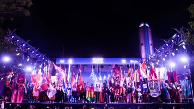 Escenario principal de la Fiesta de las Colectividades de noche, con el Monumento a la Bandera iluminado de fondo