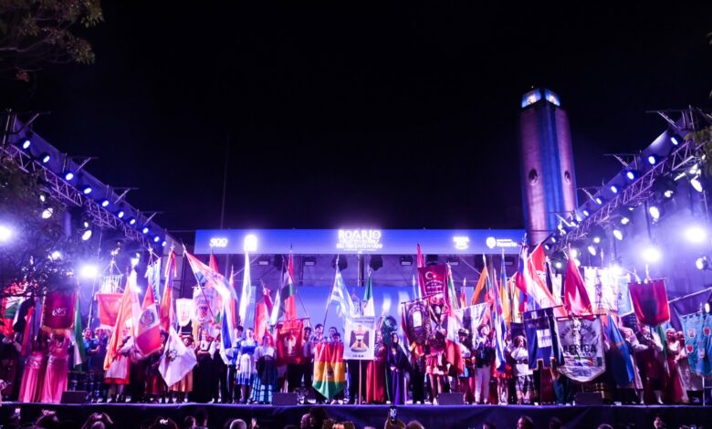 Escenario principal de la Fiesta de las Colectividades de noche, con el Monumento a la Bandera iluminado de fondo