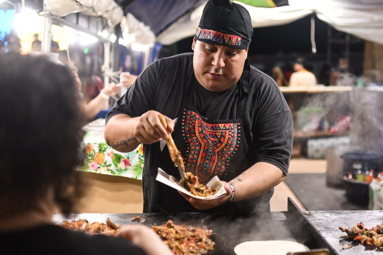 Cocinero sirviendo comida en un stand de la Fiesta de las Colectividades de Rosario