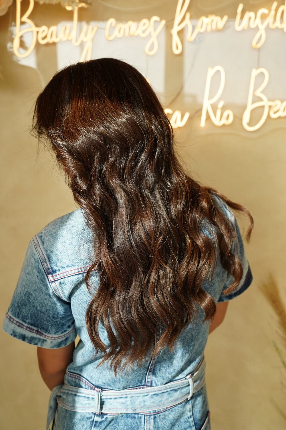 Mujer de espaldas con pelo largo ondulado castaño chocolate con brillo