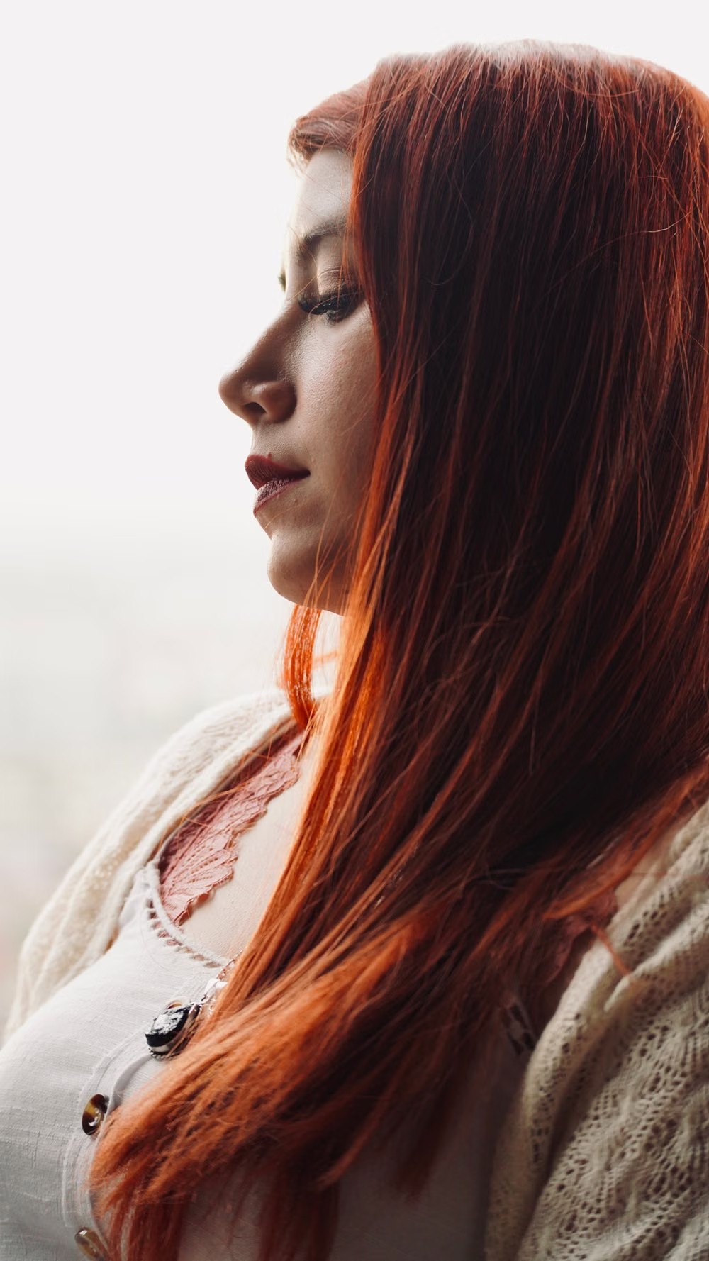 Mujer de perfil con pelo largo lacio cobrizo