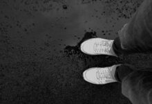 Zapatillas blancas sobre el asfalto mojado después de la lluvia