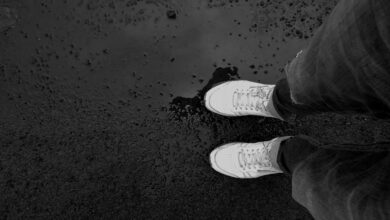 Zapatillas blancas sobre el asfalto mojado después de la lluvia