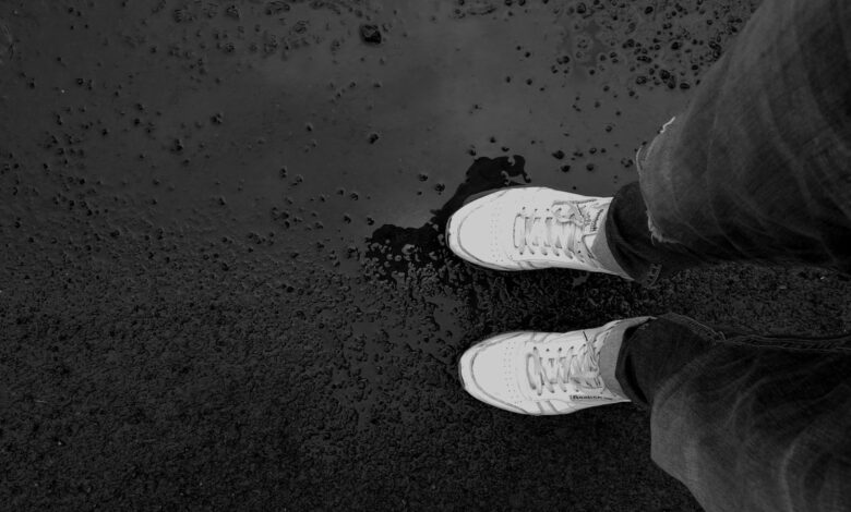 Zapatillas blancas sobre el asfalto mojado después de la lluvia