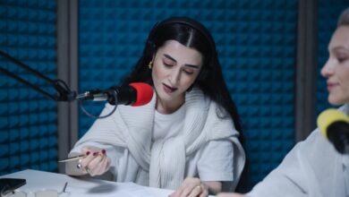 Dos mujeres conducen un programa de radio frente a micrófonos profesionales en un estudio